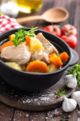 Meat stewed with carrots and potatoes in sauce on wooden rustic background