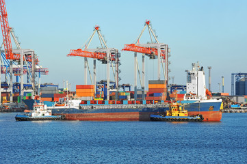 Naklejka premium Tugboat assisting bulk cargo ship