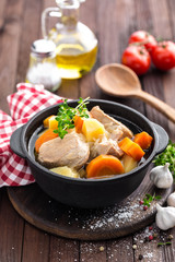 Meat stewed with carrots and potatoes in sauce on wooden rustic background