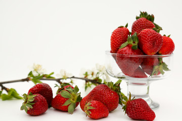 Ripe strawberry in a glass vase and a sprig of flowering tree