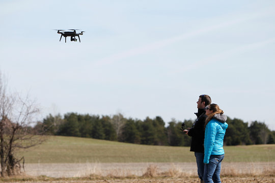 Two people watching a hovering drone