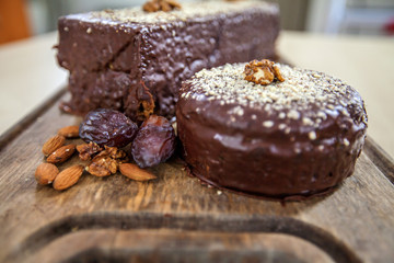 Two delicious chocolate cakes with walnuts and plumps are standing on a wooden board.