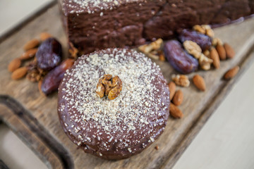 We can see a nicely decorated chocolate cake with walnut crumbles on a wooden board.