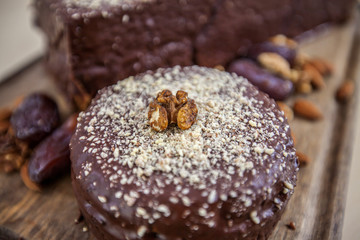 Chocolate cakes with walnuts crumble is standing on a wooden board. 