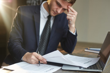 Portrait of modern businessman busy working with papers: reading contract documentation, analyzing...