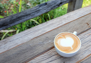 A cup of coffee on wooden table in the garden background