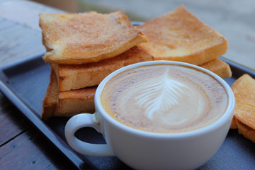 A cup of coffee with bread on wooden background