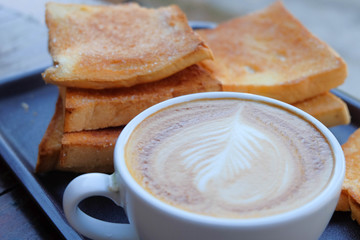 A cup of coffee with bread on wooden background