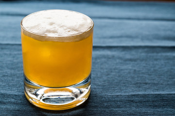 Whiskey Sour Cocktail with foam and blue backround