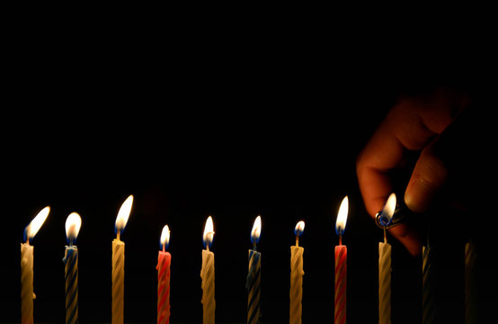 Human hand is lighting the birthday candle in the darkness