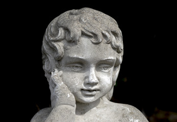 Fototapeta na wymiar Vintage stone garden statue of young girl with hand on cheek, thoughtful beautiful expression