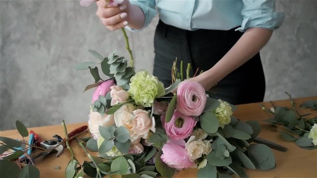 Close up florist making a bouquet of flowers.Peone and roses, focus on the bouquet