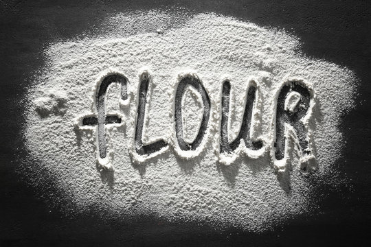 Word made of flour on dark table