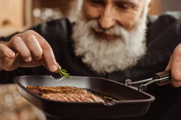  Man cooking steaks © LIGHTFIELD STUDIOS