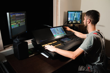 A lighting engineer works with lights technicians control on the concert show. Professional light...