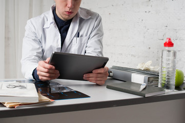 Doctor filling medical online form in the laptop tablet. The works at the hospital