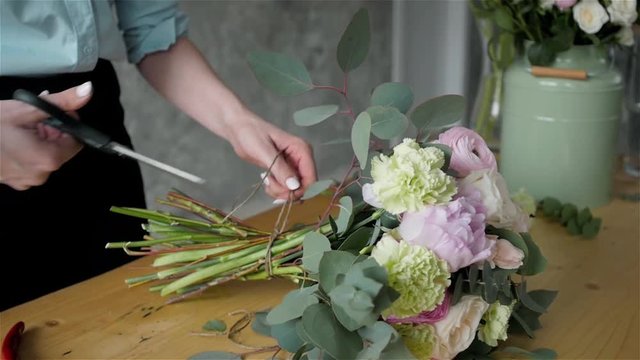 Close up florist making a bouquet of flowers.Peone and roses, focus on the bouquet