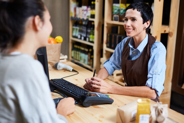 Smiling vendor talking to customer in supermarket