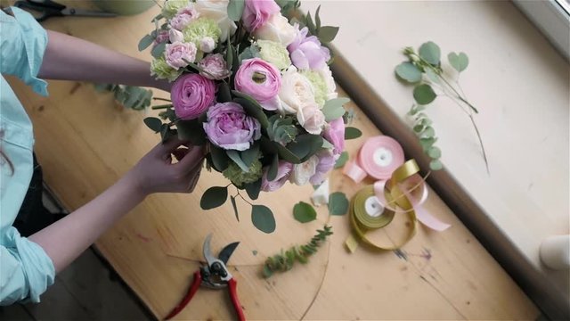 Top View of Female florist making beautiful bouquet at flower shop, peone and rose flower composition for wedding