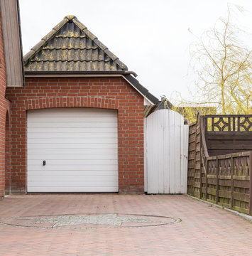 Garage mit Pfannendach und weißem Tor