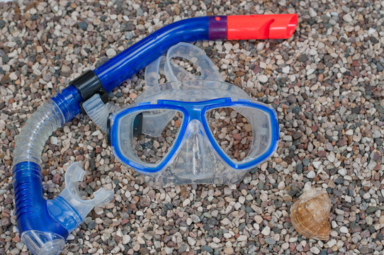 Diving mask with snorkel and shell on beach