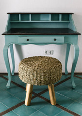 Blue vintage table of drawers stands near white wall