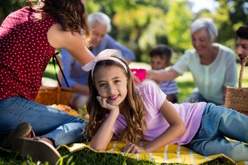 Girl resting on blanket besides family enjoying the picnic