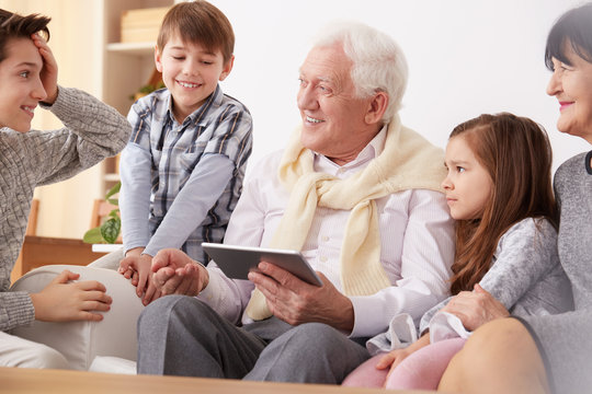 Grandchildren teaching grandpa to use a tablet