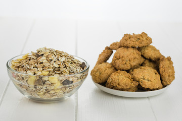 Glass bowl with granola and white bowl with homemade biscuits on a wooden table.