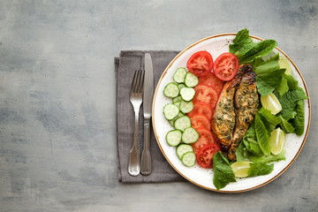 Baked salmon in a lemon-honey dressing with herbs served with fresh vegetables and salad 

