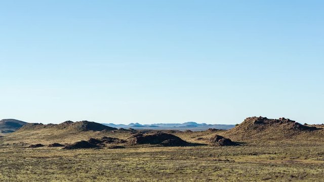 A static timelapse of vast arid landscape scene and wide open spaces with mountains and rocky hills in a semi-desert location at sunset while the night falls