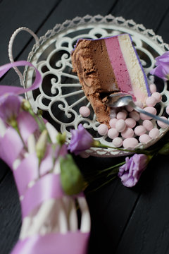 Piece of blueberry pie take with spoone near flowers on black wooden background
