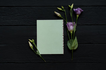 Green envelope template on black wooden background with flowers 