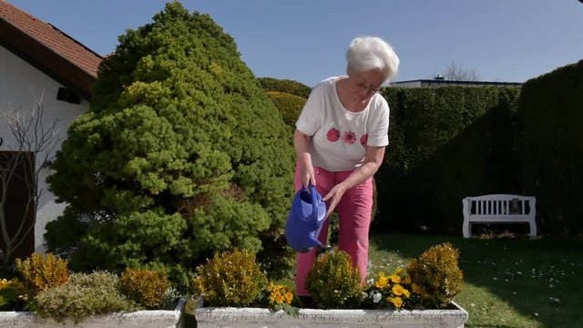 Seniorin beim Blumen gie&szlig;en