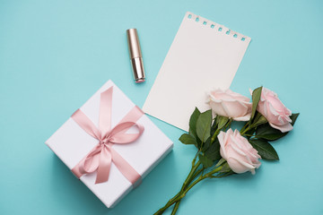 Mother's Day concept. Bouquet of pink roses with gift box and lipstick. Blank paper note for copy...