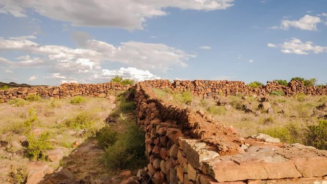 A wide-angle push-in timelapse shot of a historical barn made with stacks of rocks and cow dung on a sunny day with scattered clouds just before a thunderstorm available on request.