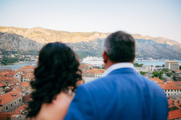 The couple is looking at the liner. The newlyweds admire the cruise liner. A viewing platform on the wall above the old town of Kotor in Montenegro.