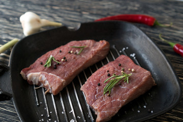 pan of fresh meat with rosemary on dark background, top view