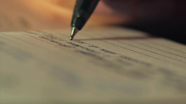 A hand with a black gel pen writes on a paper. Concept for school projects.