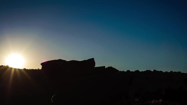 A linear push-in timelapse at sunrise with abstract rocks silhouetted in the foreground against a blue sky available on request.