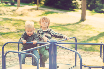Fototapeta na wymiar Two happy boys playing on playground in a park. Toned.