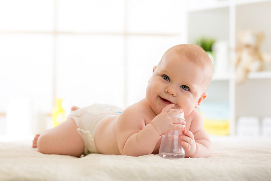 Cute baby with feeding bottle on bed