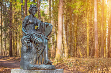 Fototapeta na wymiar A female copper statue of a deity with a harp in the woods