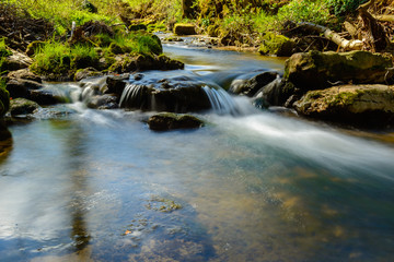 Fototapeta na wymiar Bach und Fluss mit kleinem Wasserfall