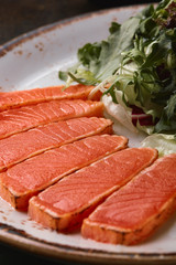 Fried slices of salmon with lettuce and sauce