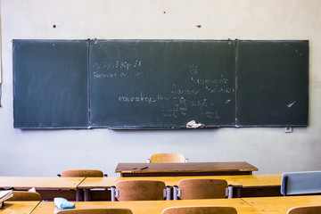 Classroom with empty wooden desks and with green board