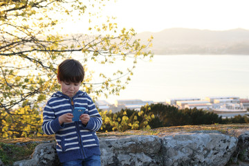 little kid playing with a smartphone in a viewpoint © M.Madriñán