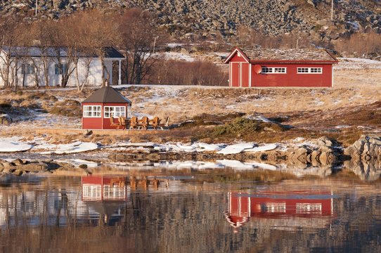 Some rorbuer reflected on the water of the near fiord in the Lofoten Islands, Norway.