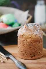 Easter cake standing on board against the basket with easter eggs.
