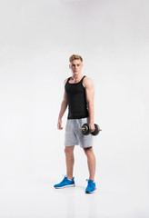 Handsome fitness man holding dumbbell, studio shot.